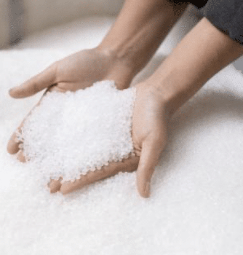 hands holding white plastic pellets